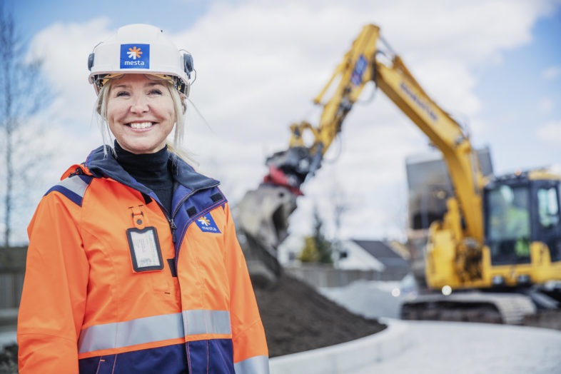 Marianne Bergmann Røren foran gravemaskin.